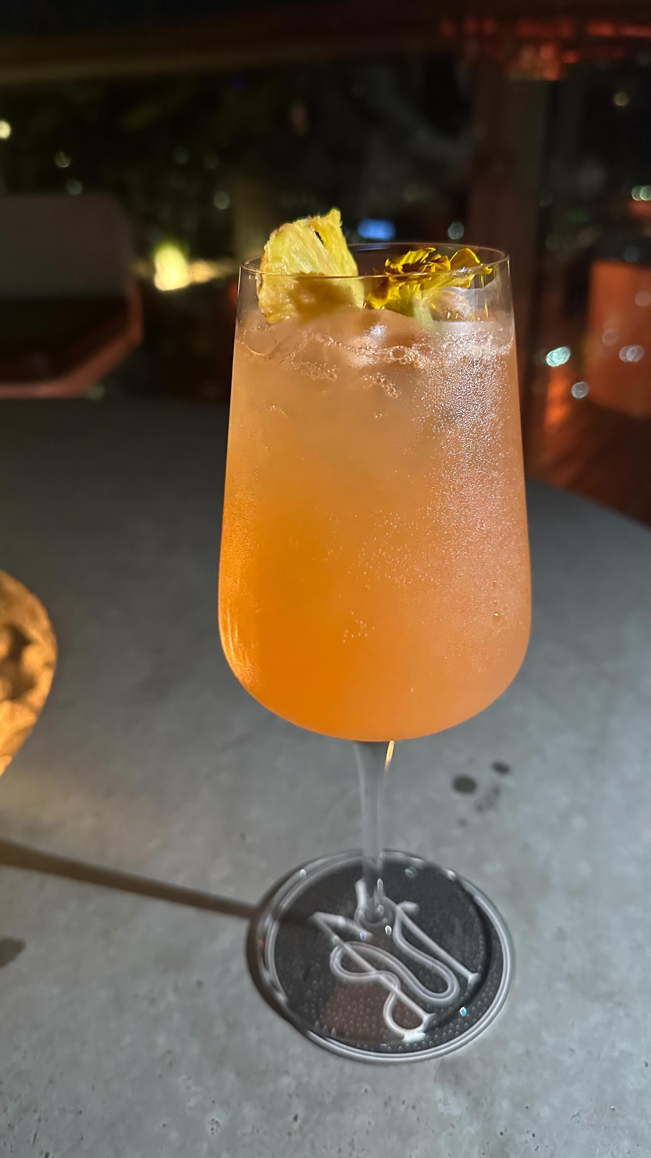 A cocktail with dried pineapple on a stone table at night
